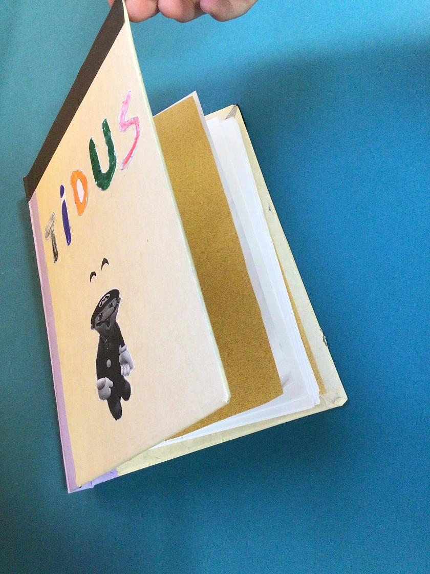 Selbst erstelltes Buch eines Schülers. Der Schüler hat seinen Namen und eine Super Mario-Figur auf die Vorderseite des Buches geklebt.