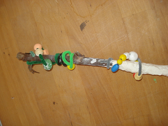 Ast mit teilweise mit Gips, Perlen und Biegeplüsch umhüllt.