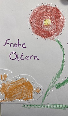 Punktschriftbild. Hase und Blume. In Schwarzschrift geschrieben: Frohe Ostern 