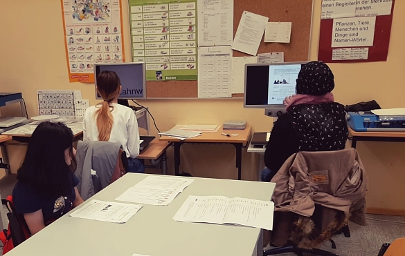 Man sieht drei Schülerinnen, welche an Arbeitsmaterialien arbeiten. Zwei von ihnen sitzen am Bildschirmlesegerät.