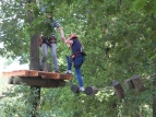 Eine Lehrkraft und eine Schülerin beim Klettern in einem Kletterpark. Die Lehrerin hilft der Schülerin bei einer Etappe. 