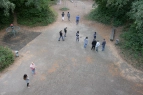 Das Bild ist aus der oberen Etage aufgenommen. Zu sehen ist der Schulhof mit mehreren Schüler*innen und Lehrkräften die eine Begehung des Schulhofes machen.
