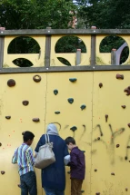Eine Lehrerin klebt mit zwei blinden Schülern farbige Klebepunkte an den Kletterturm, je nach dem ob ihnen dieser gefällt oder nicht. 