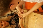 Eine Lehrerin und ein Schüler versuchen aus kleinen Stäben ein Baumhaus zu bauen.