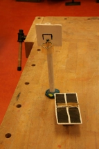 Auf einer Werkbank stehen von Schüler*innen gebaute Miniatur-Gegenstände die auf den Schulhof kommen sollen, hier zu sehen ein Basketballkorb sowie eine Tischtennisplatte.