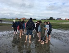 Die Schüler*innen machen eine Wattwanderung und stehen in einer größeren Gruppe zusammen. 