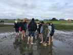 Die Schüler*innen machen eine Wattwanderung und stehen in einer größeren Gruppe zusammen. 