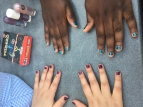 Vier Hände mit bemalten Fingernägeln in blau und lila. 