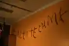 Zu sehen sind aus Pfeifenputzern geformte Buchstaben, die in einem abgedunkelten Raum an einer langen Leine befestigt sind. Der Schatten an der Wand zeigt den Schriftzug Fritz will zur Technik.