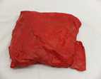 Zu sehen ist ein rot angemaltes Gipsobjekt, was aus einem alten T-Shirt zu einem Quadrat geformt wurde. Die Stoffstrukturen sind teilweise zu erkennen. Es befindet sich auf einem weißen Untergrund aus Stoff.