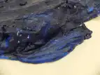 Zu sehen ist der Ausschnitt eines blau angemalten Gipsobjekts, was aus einem alten T-Shirt geformt wurde. Die Stoffstrukturen sind teilweise zu erkennen. Es befindet sich auf einem weißen Untergrund aus Stoff.
